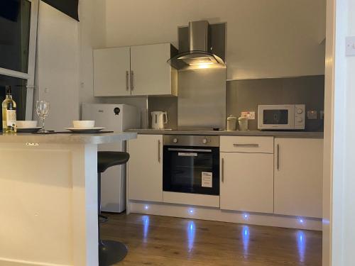 a kitchen with white cabinets and a counter top at The Sleeping Lion - Dunoon Holiday Home in Dunoon