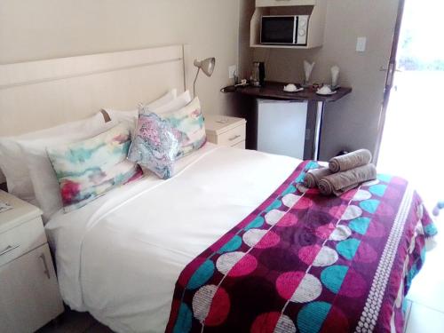 a bedroom with a white bed with a colorful blanket at LightStone Guesthouse in Centurion