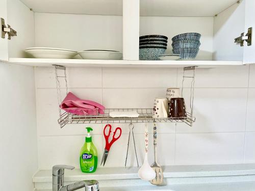 - un évier de cuisine avec une étagère avec de la vaisselle et des ciseaux dans l'établissement Gurye Junsung Resort, à Gurye
