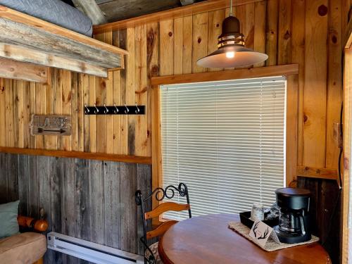 Habitación de madera con mesa y ventana en Whitetail Creek Camping Resort en Lead