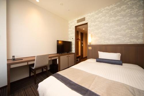 a bedroom with a bed and a desk with a computer at Hotel Ichibata in Matsue