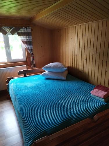 Cama en habitación de madera con manta azul en Говерлянка, en Vorokhta