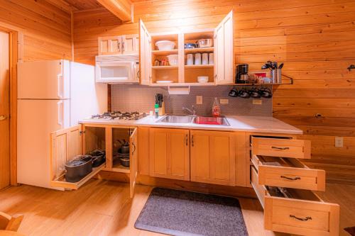 a kitchen with wooden cabinets and a white refrigerator at Cabin #4 The Wolves Den - Pet Friendly- Sleeps 6 - Playground & Game Room in Payson