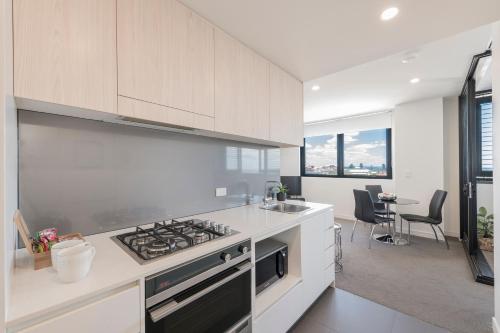 a kitchen with white cabinets and a stove top oven at Astra Apartments Newcastle Beach in Newcastle