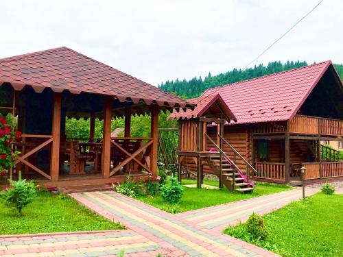 a large wooden cabin with a red roof at Plavianska Sadyba in Plav'ya