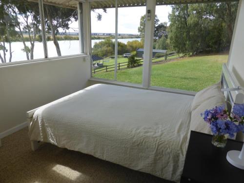 a bedroom with a bed and a large window at Riverfront Holiday House in Wellington East