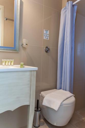 a bathroom with a toilet and a blue shower curtain at Villa Nostalgia Lentas No1 in Léntas