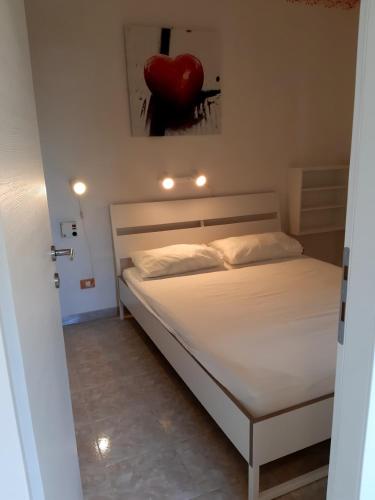 a bedroom with a white bed with a red heart on the wall at Villa Ca'Bianca in Bibione