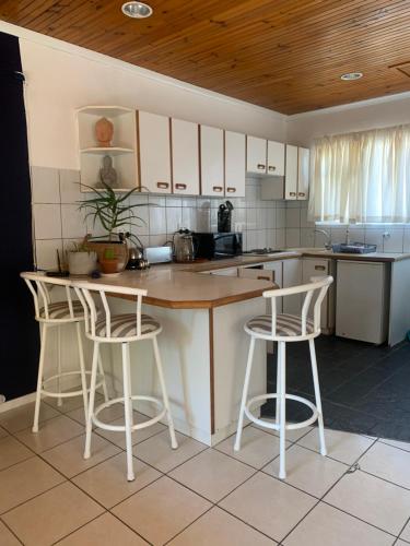 a kitchen with white cabinets and bar stools at The Little Hideaway Guesthouse in Stellenbosch