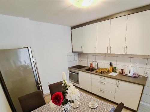 a kitchen with white cabinets and a table with flowers on it at Apartment Andrej in Tomislavgrad