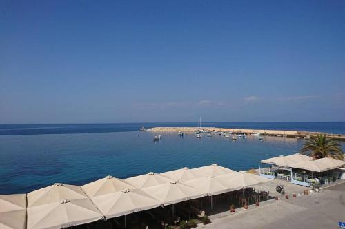 KORONI MARE -Sea view apartment/διαμέρισμα με θέα στην θάλασσα في كوروني: ميناء فيه مظلات بيضاء وقوارب في الماء