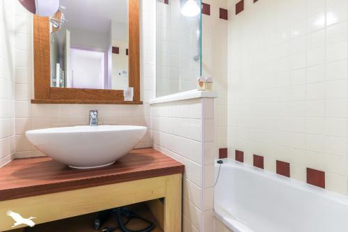 La salle de bains est pourvue d'un lavabo blanc et d'une baignoire. dans l'établissement Appartement cosy, à Moliets-et-Maa