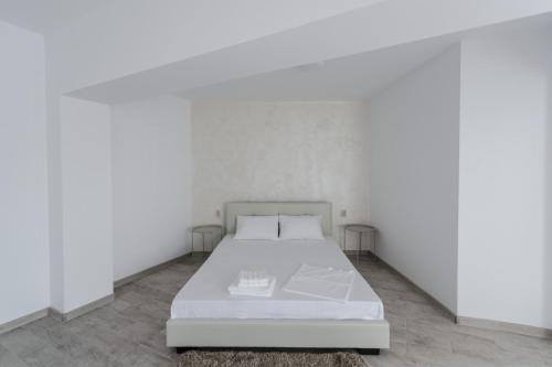 ein weißes Bett in einem Zimmer mit weißen Wänden in der Unterkunft Toma Residence in Eforie Nord