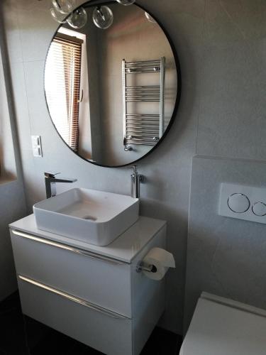 a bathroom with a white sink and a mirror at Apartament Latarnik- BIG in Gąski