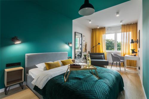 a blue bedroom with a bed and a table at Barska 69 Apartments in Krakow