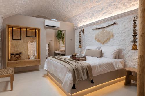 a bedroom with a large white bed and a brick wall at Kaminos Boutique Hotel in Symi