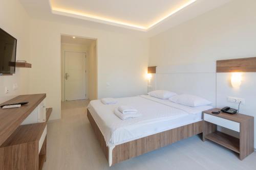 a white bedroom with a bed and a television at Soothe Hotel in Kalkan