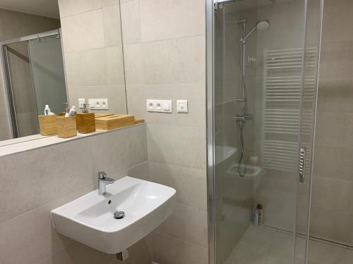 ein weißes Bad mit einem Waschbecken und einer Dusche in der Unterkunft Teehouse Golf Apartment in Čeladná