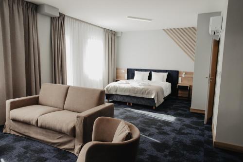 Habitación de hotel con cama y sofá en Molto Bene Hotel & Restaurant en Skórcz