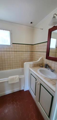 a bathroom with a sink and a tub and a mirror at Le Petit Mas de Grimaud in Grimaud