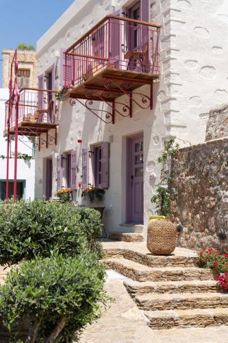 a white building with a balcony and stairs at Kaminos Boutique Hotel in Symi