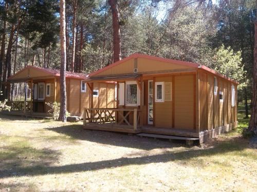 a small yellow cabin in the woods at Camping Cobijo in Vinuesa