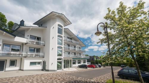 a white building with cars parked in a parking lot at Landhotel Kristall in Bad Marienberg