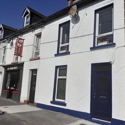 a white building with a blue door on a street at Tirchonaill Townhouse in Donegal