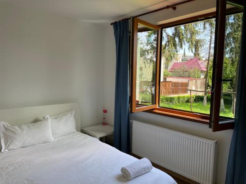 a bedroom with a white bed and a window at Peles Green Apartment in Cluj-Napoca