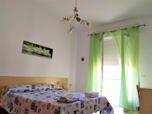 Schlafzimmer mit einem Bett mit grünen Vorhängen und einem Fenster in der Unterkunft B&B Casa Valentina a Linguaglossa in Linguaglossa