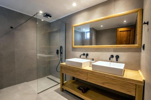 y baño con 2 lavabos, espejo y ducha. en Cato Agro 2, Seafront Villa with Private Pool, en Karpathos