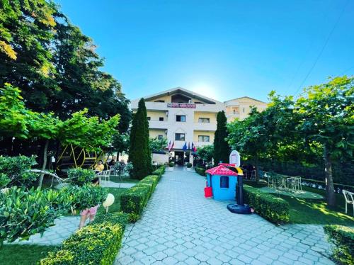 una pasarela en un parque con un edificio al fondo en Hotel Ambasador Garden, en Lezhë
