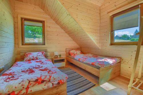 een slaapkamer met 2 bedden in een houten hut bij Domki inNatura in Istebna