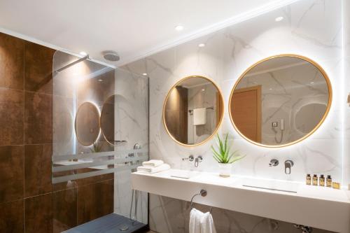 a bathroom with two sinks and two mirrors at Alexandra Beach Spa Resort in Potos