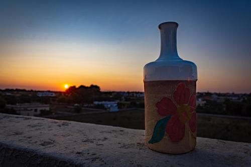 a bottle sitting on a ledge with the sunset in the background at Antica Casina B&B di Charme in Pulsano