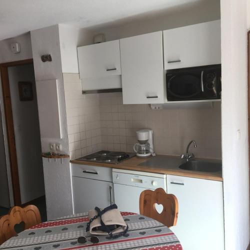 une cuisine avec des armoires blanches, une table et un micro-ondes dans l'établissement Appart st François longchamp, à Saint-François-Longchamp
