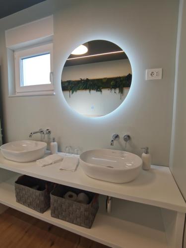 a bathroom with two sinks and a large mirror at Villa Green Forest with wellness and heated salty pool in Hum