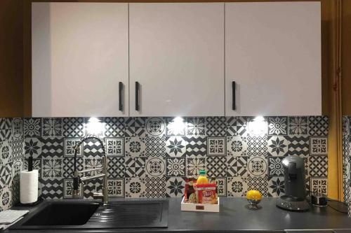 une cuisine avec des armoires blanches et du carrelage noir et blanc dans l'établissement Au Cœur du Marché, à Boulogne-sur-Mer