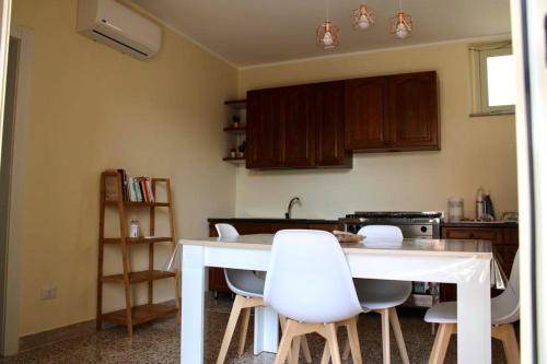 una cucina con tavolo bianco e sedie bianche di La Maison de Mimì a Condofuri Marina