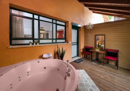 ein großes Bad mit einer großen Badewanne und einem Tisch in der Unterkunft Zimmer & Spa Kesem Hamaga in Bethlehem