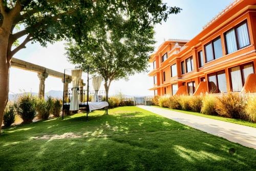 a bench sitting in the grass next to a building at Fateh Garh Resort by Fateh Collection in Udaipur