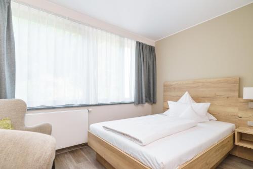 a bedroom with a white bed and a window at Hotel Forsthaus Grüna Betreibergesellschaft mbH in Chemnitz