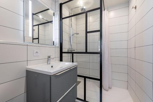 une salle de bain blanche avec un lavabo et un miroir dans l'établissement Appt lumineux - Avec balcon à 400m de la plage, à Courseulles-sur-Mer