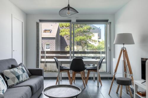 un salon avec une table et des chaises et une fenêtre dans l'établissement Appt lumineux - Avec balcon à 400m de la plage, à Courseulles-sur-Mer