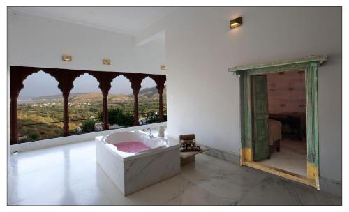 a bathroom with a tub and a large mirror at Fateh Garh Resort by Fateh Collection in Udaipur