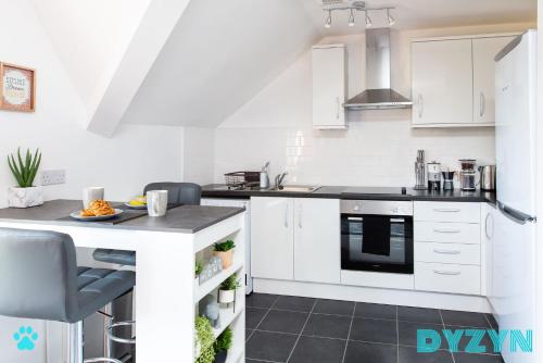 a kitchen with white cabinets and a black counter top at River View - 1 Bed Serviced Apartment in Cardiff City Center - Street Parking - By DYZYN in Cardiff