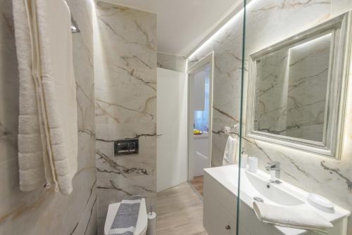 a white bathroom with a sink and a mirror at 1571_SUITES A1 in Nafpaktos