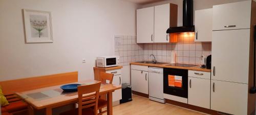 cocina con armarios blancos, mesa, mesa y sillas en Haus Wegleitner, en Apetlon