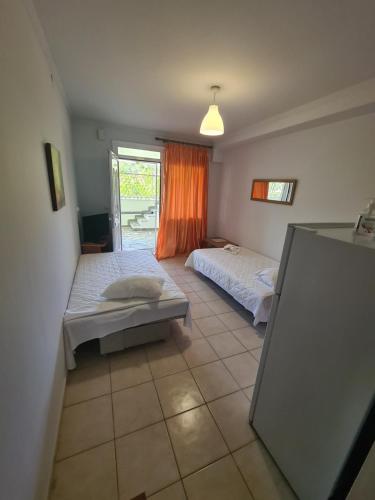 1 dormitorio con 2 camas y cortina de color naranja en Villa Valeria Thassos, en Limenas