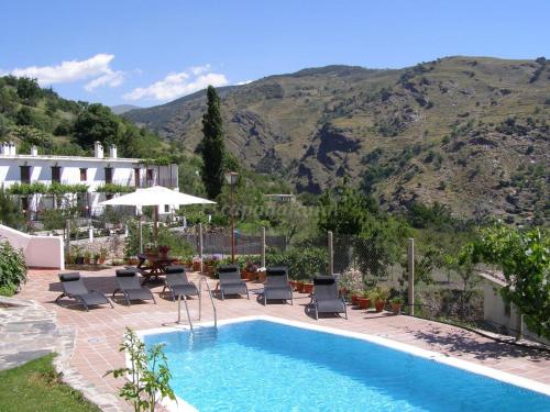 una piscina con tumbonas y una montaña en CASASBLANCAS. Casa nr 8, en Alpujarra de la Sierra